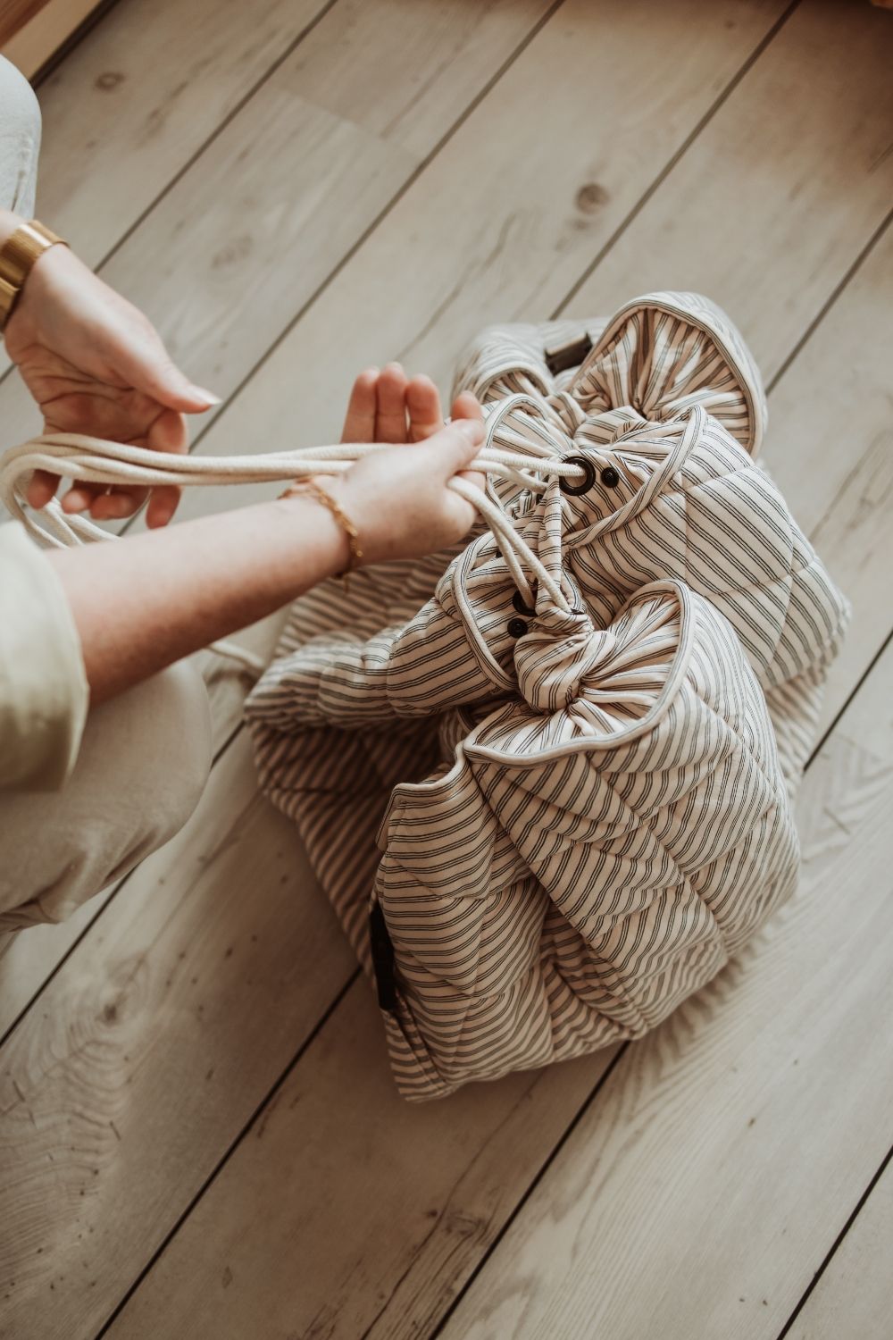 soft stripes blue organic babymat, person is closing the bag with a wrope