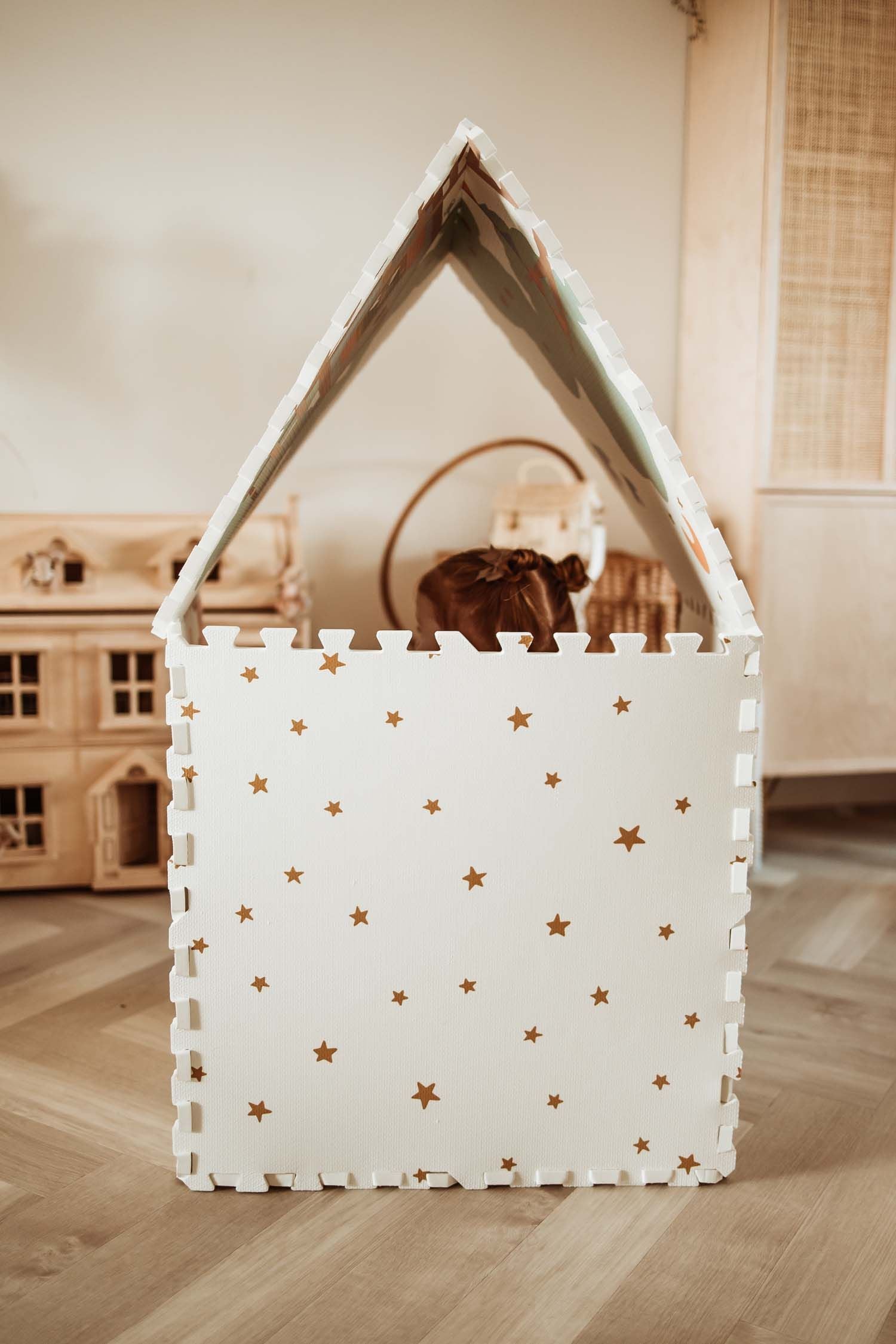 EEVAA Treehouse puzzlemat made into a playhouse, outside print stars, child is sitting in the playhouse