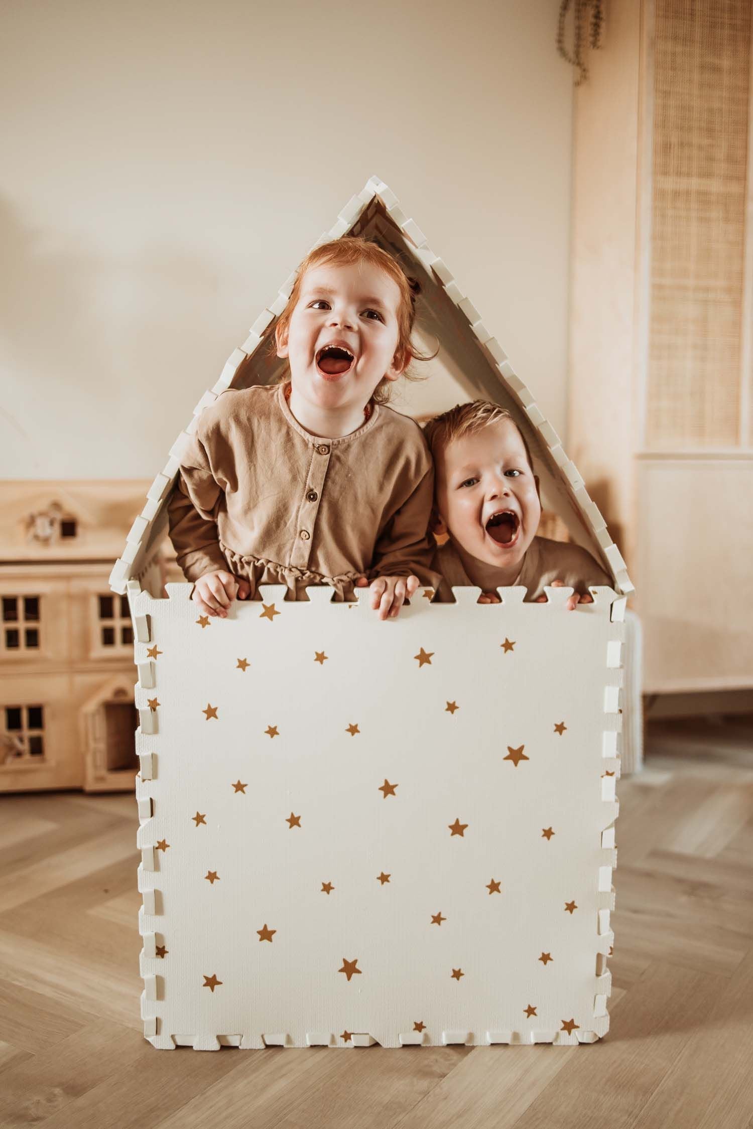 EEVAA Treehouse puzzlemat made into a playhouse, outside print stars, children are sitting in the playhouse