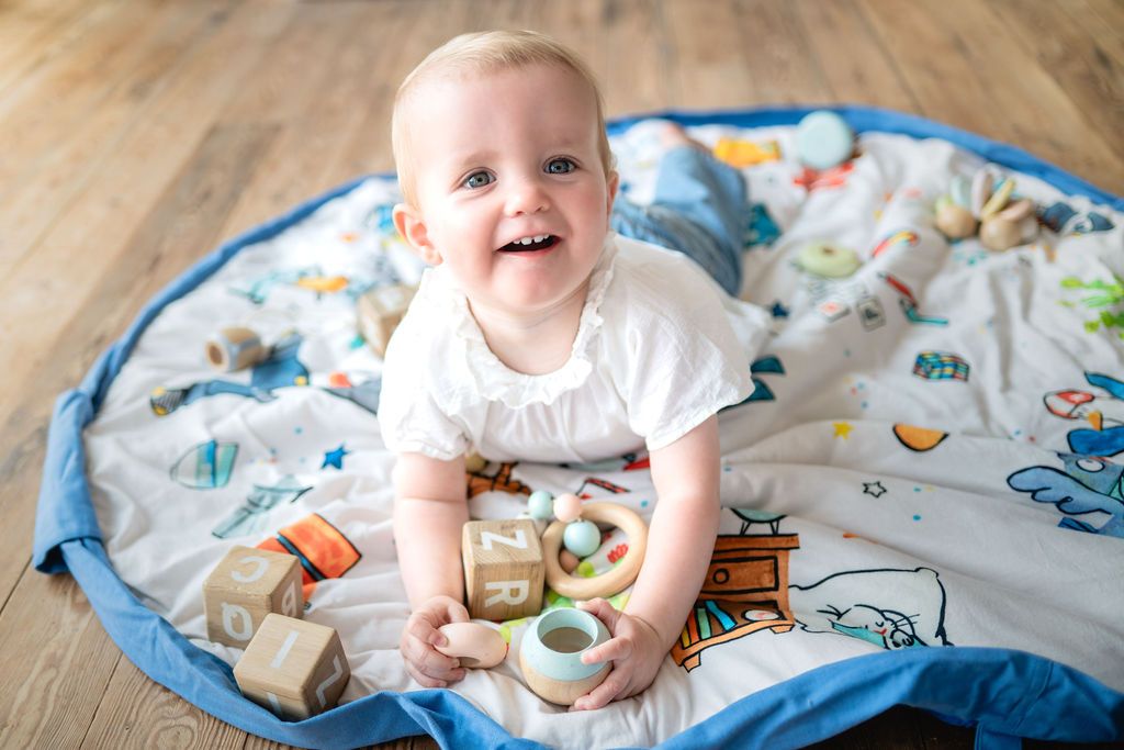 soft Puce&Pilou by Moulin Roty, child is down on the mat, playing with wooden toys