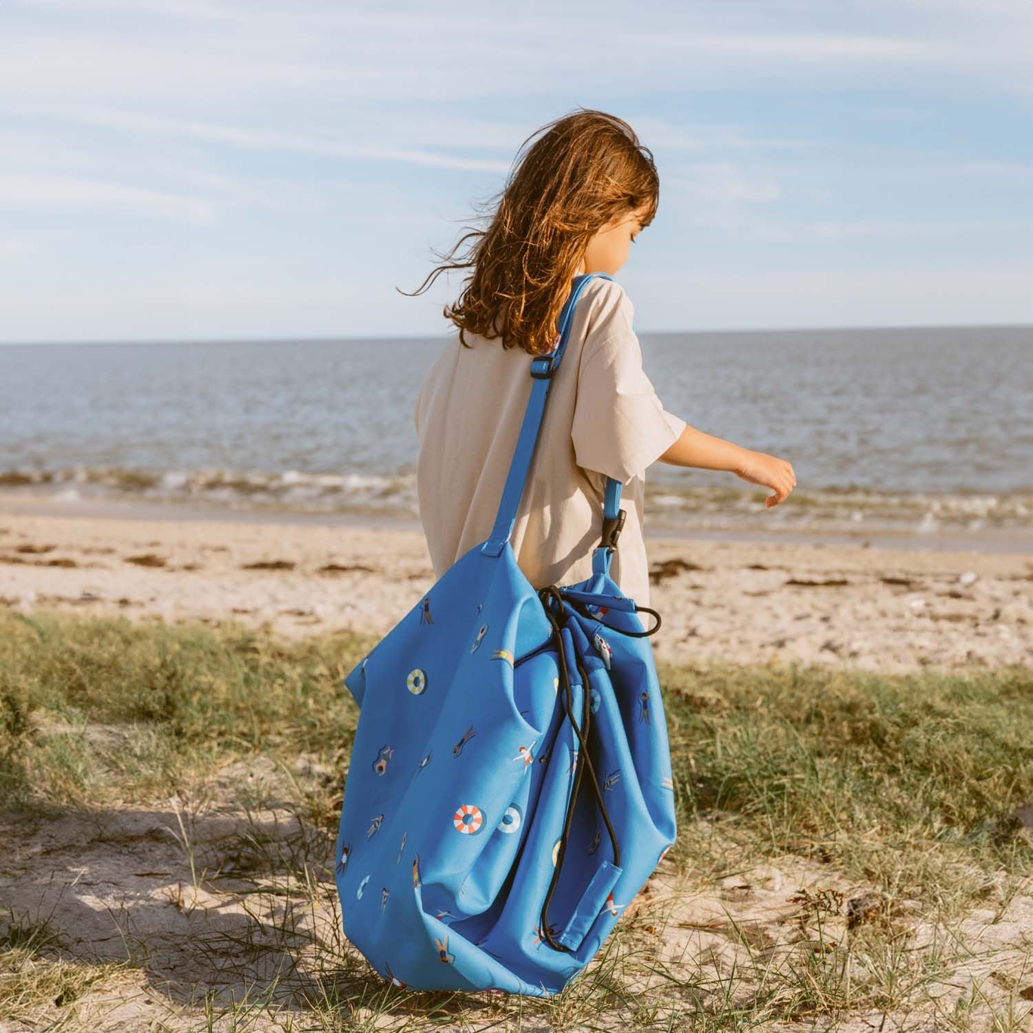 swim fun outdoor beach bag, child is carrying the bag on her shoulder with a shoulderstrap