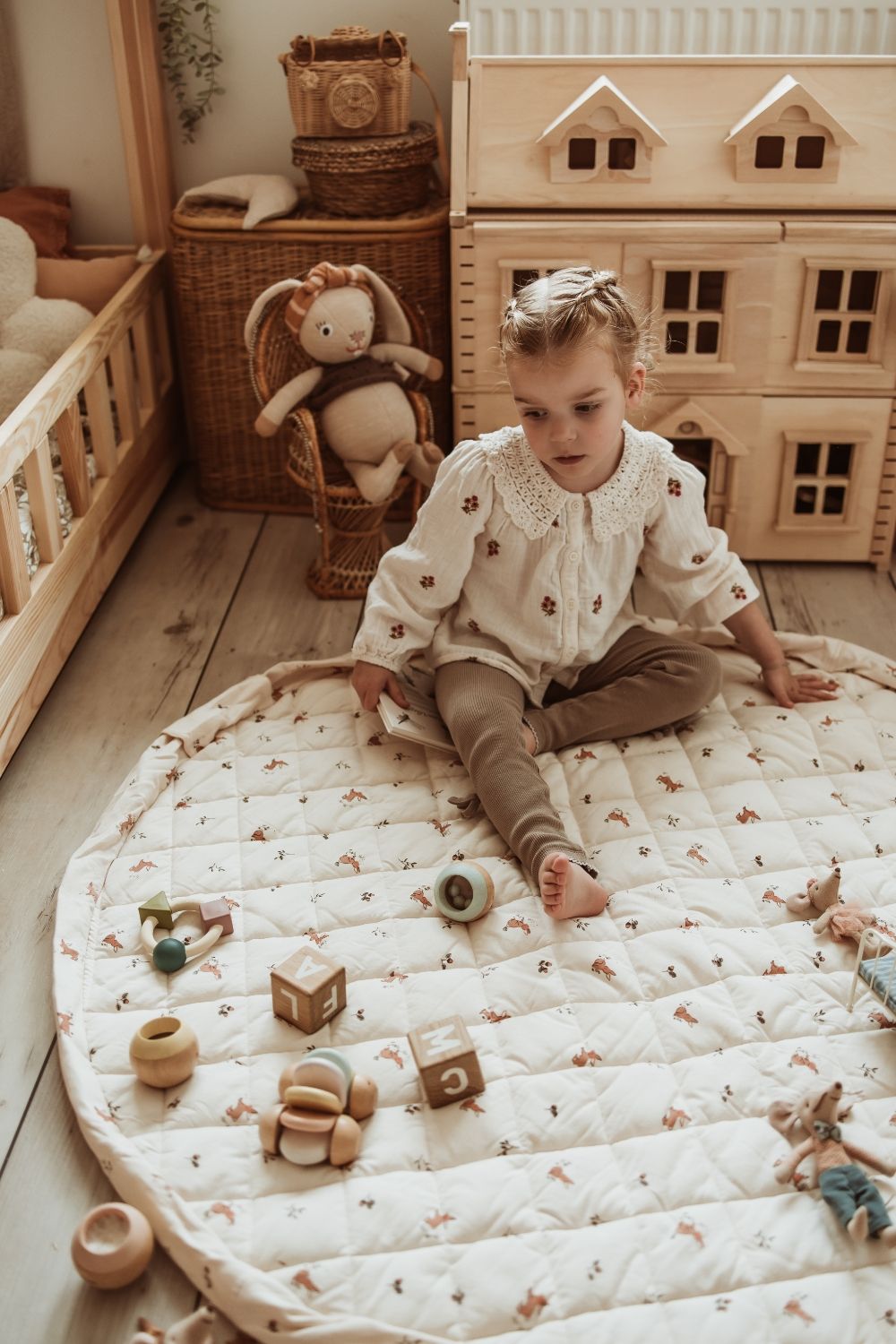 rabbit soft organic babymat, open on floor in kidsroom, child is playing with wooden toys, mouse cuddles, victorian playhouse
