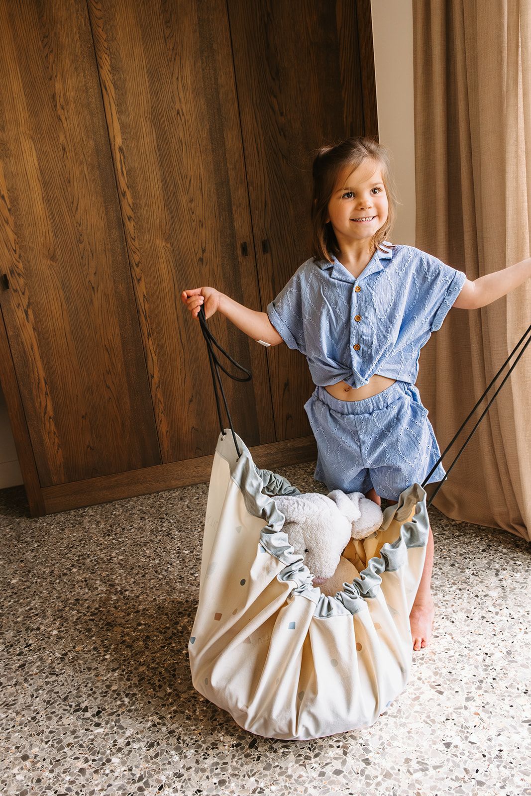 worldmap colors toy storage bag and playmat, child is closing the bag, filled with cuddles
