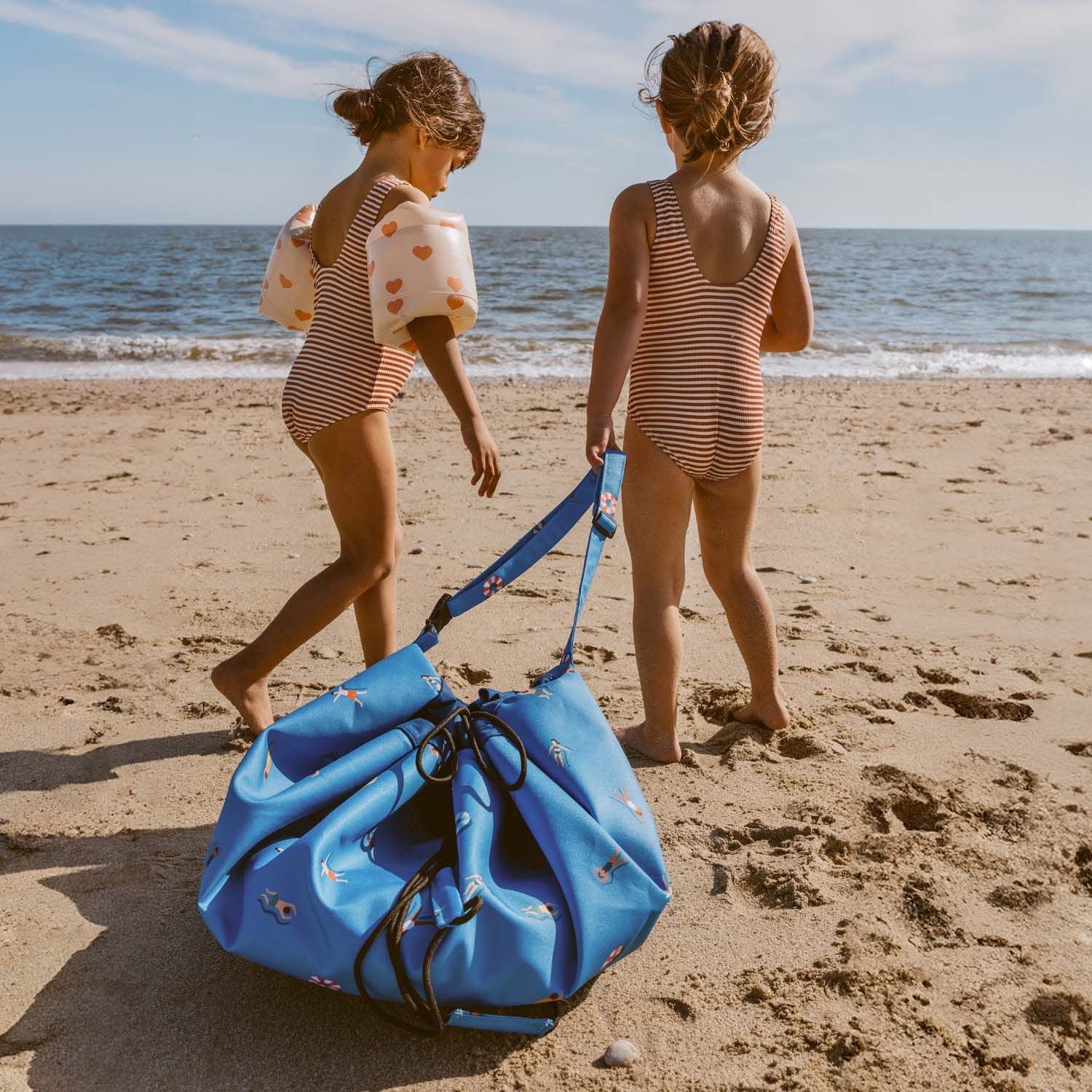 swim fun outdoor beach bag, children in swim suits are carrying the closed bag over the sand