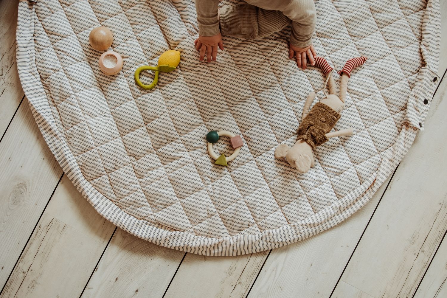 soft stripes blue organic babymat, baby is sitting on the open mat on floor, wooden toys and mouse cuddle