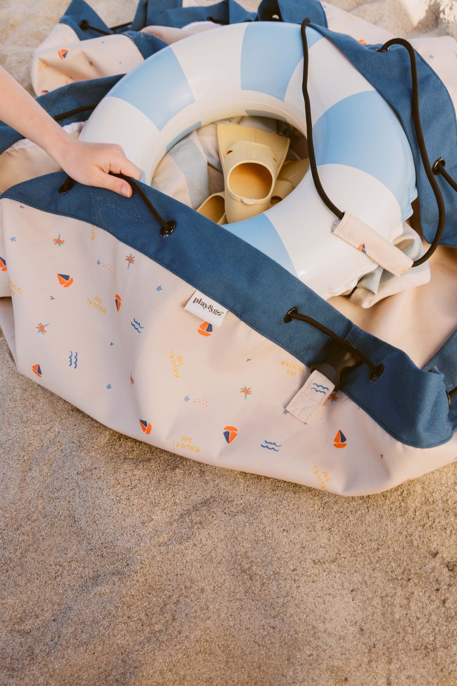 magical days outdoor beach bag, child is placing toys and swimming band in the bag