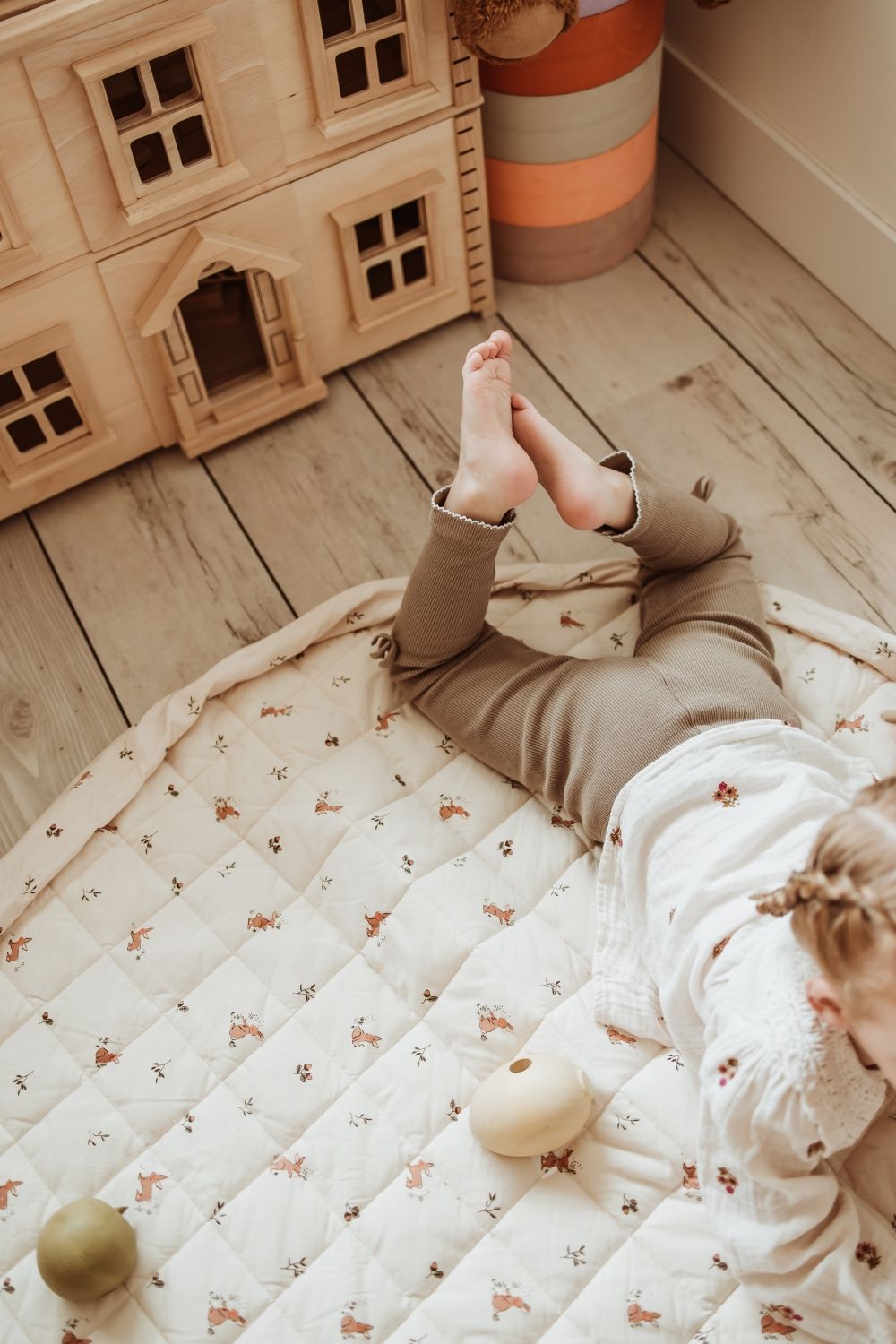 rabbit soft organic babymat, open on floor in kidsroom, child is lying on the mat, victorian playhouse, colored blocks