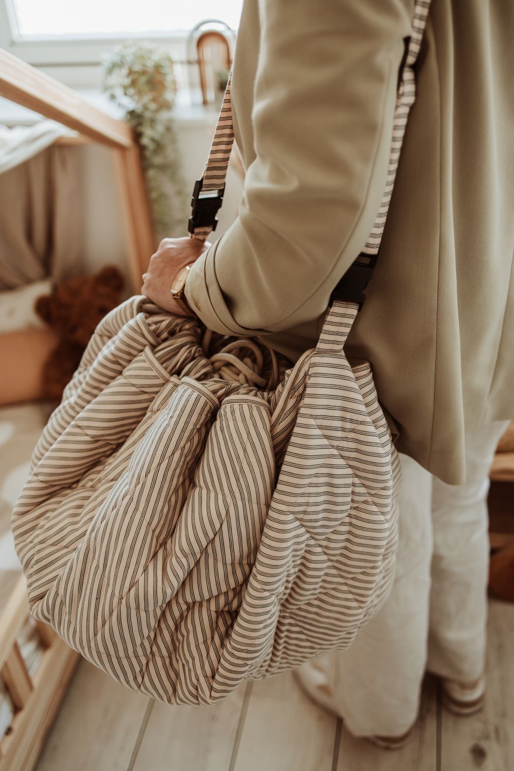 soft stripes blue organic babymat, person is carrying the bag with the shoulder strap