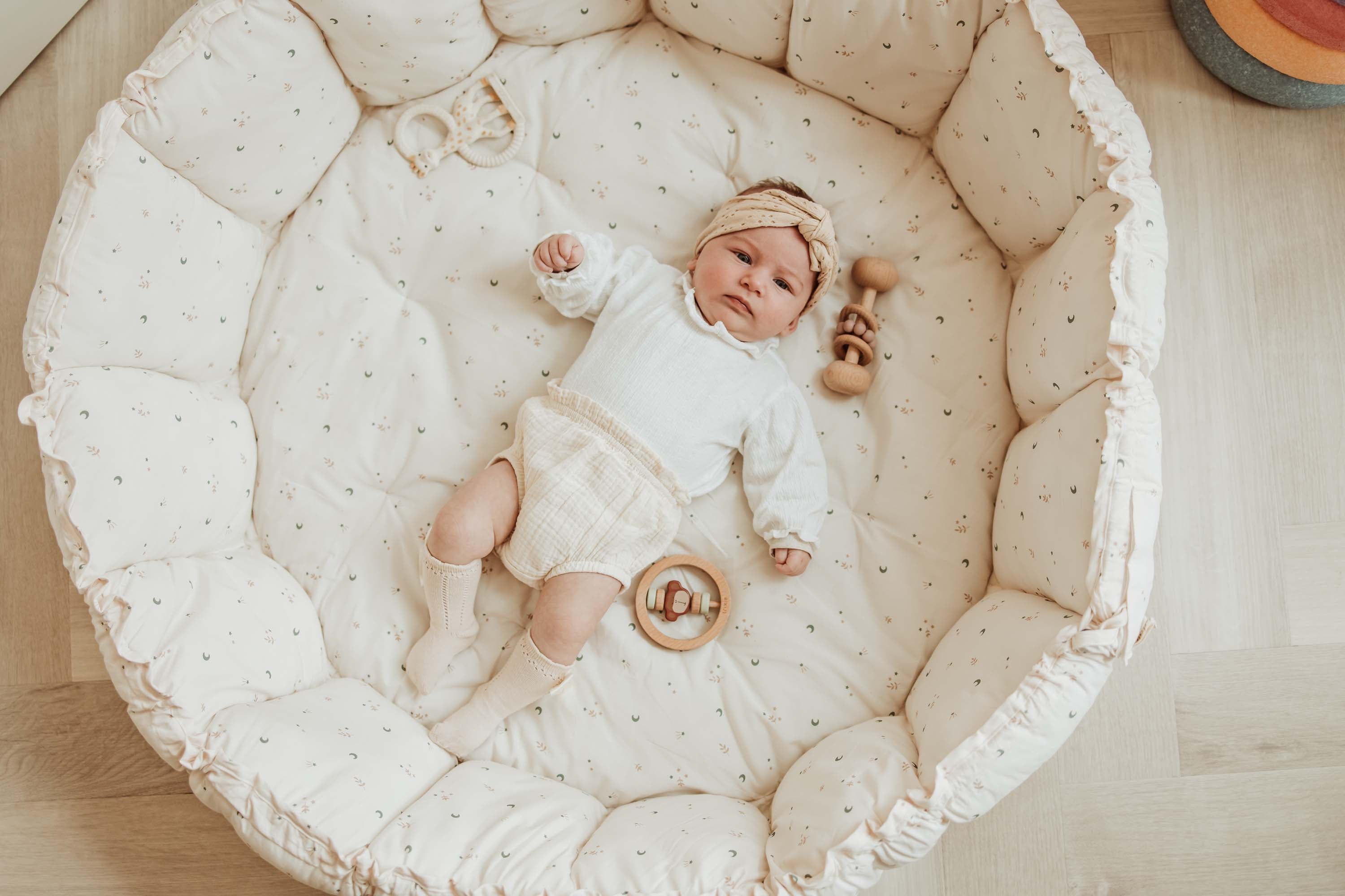 A baby laying at a soft dotted baby mat.