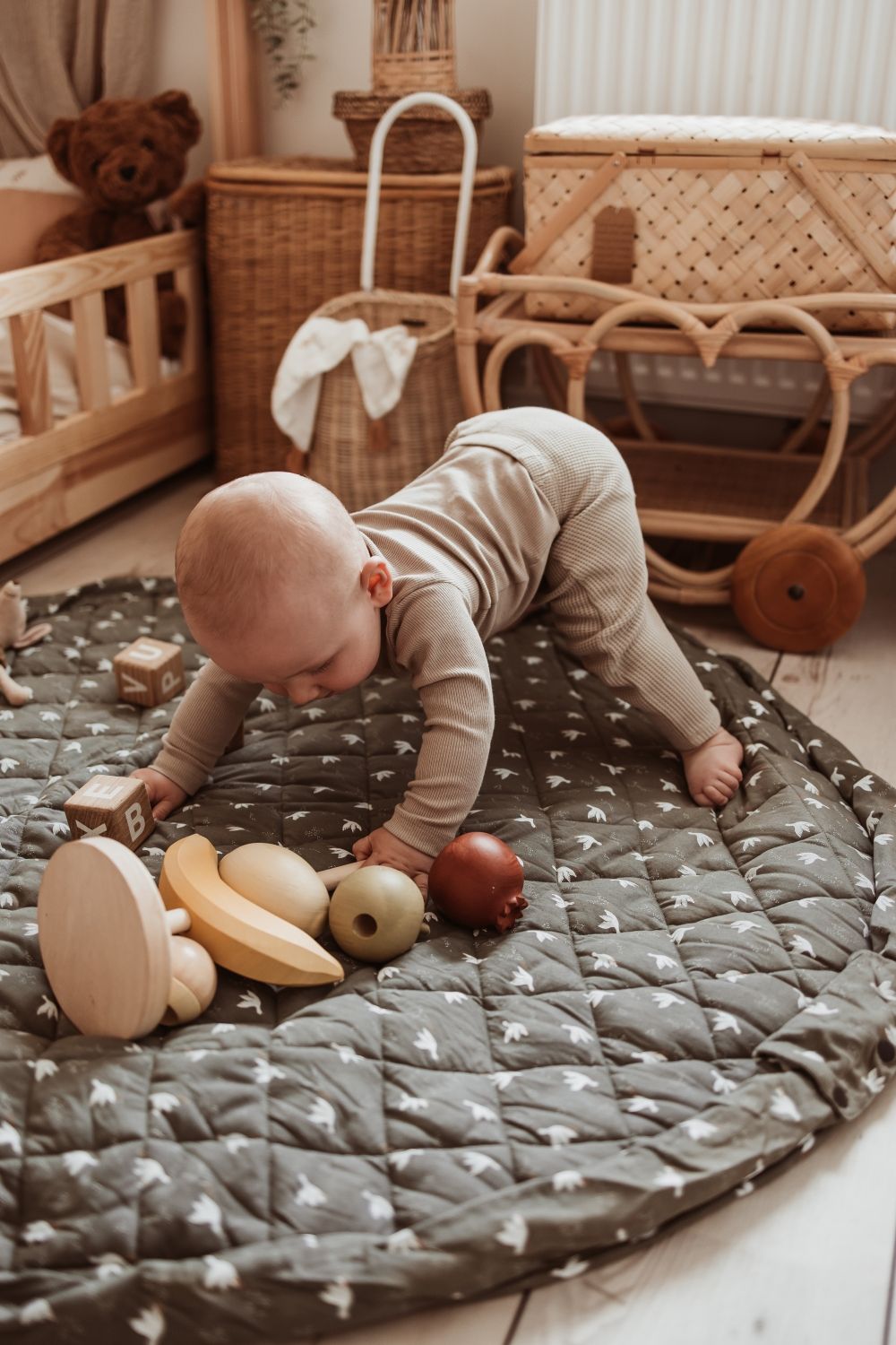 birds soft organic babymat, open on floor in kidsroom, little child is playing on the mat with wooden fruit toys