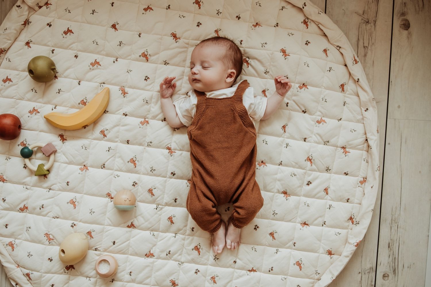 rabbit soft organic babymat, open on floor, little baby is sleeping on the mat, wooden fruit toys