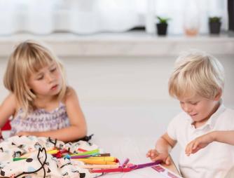 two kids sitting on a table and playing with different toys.