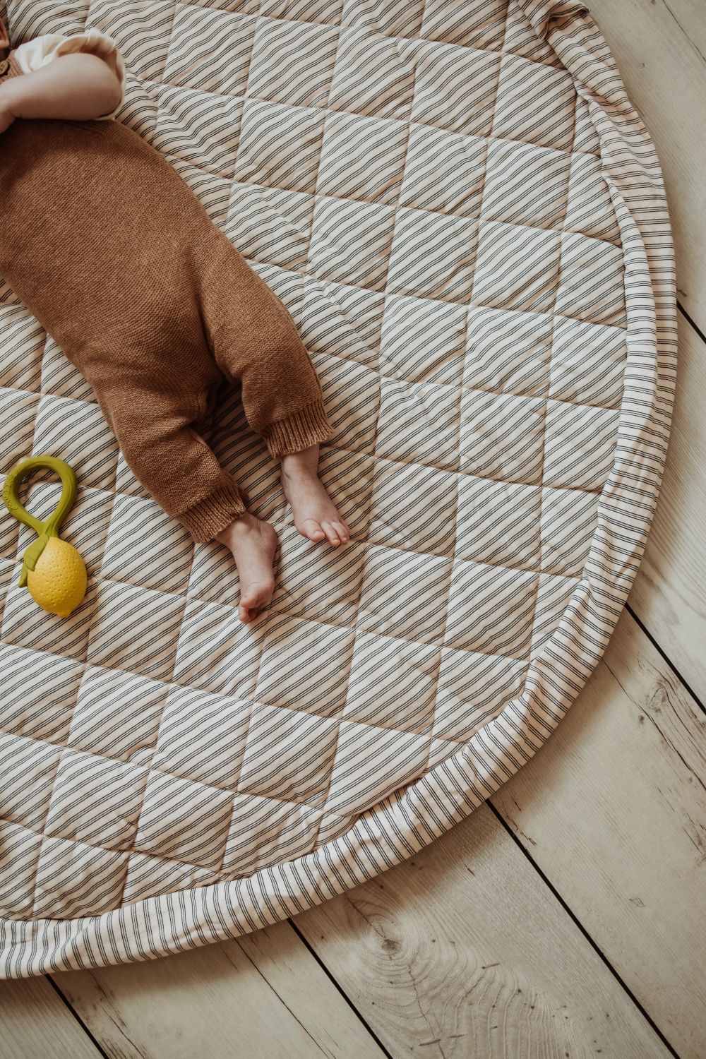 soft stripes blue organic babymat, baby is sleeping on the mat, lemon toy