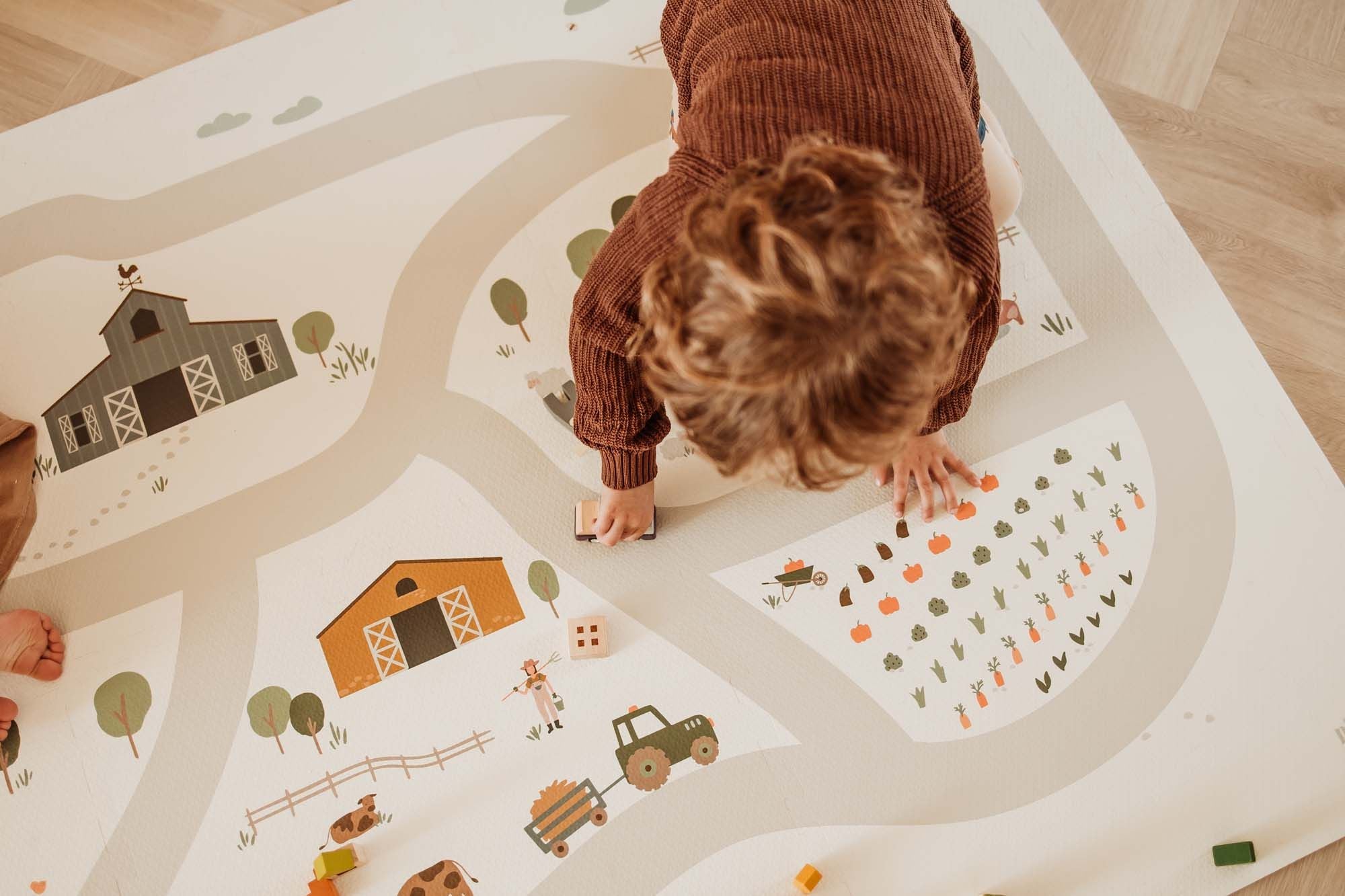 EEVAA farm puzzlemat, child is playing with a wooden car on the road of the mat