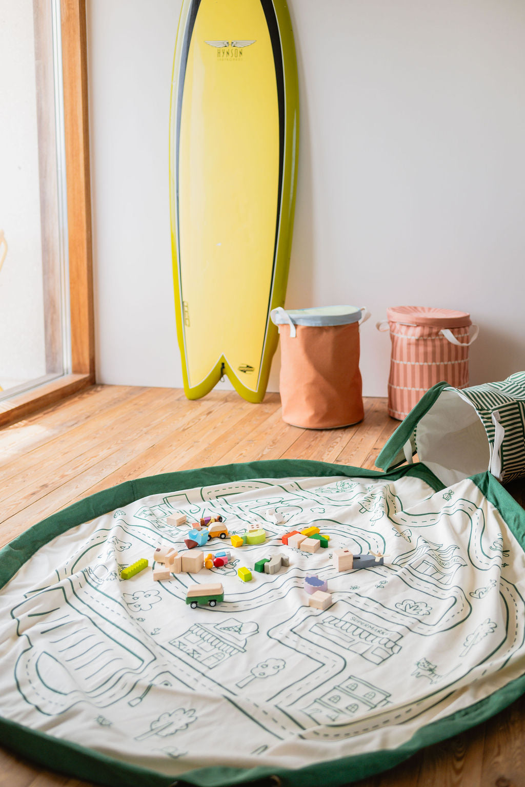 soo roadmap, open basket and open mat on the floor, wooden toys, soo fairyworld and zoo and surfboard against the wall