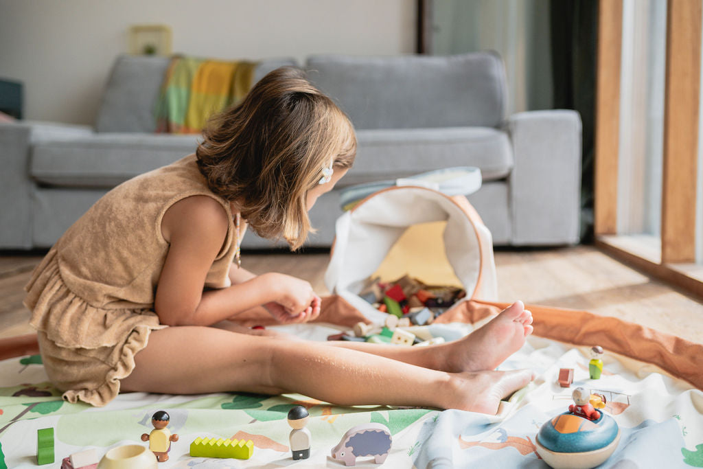 soo zoo, open basket and open mat, lots of toys, child is sitting on the mat while playing with the toys