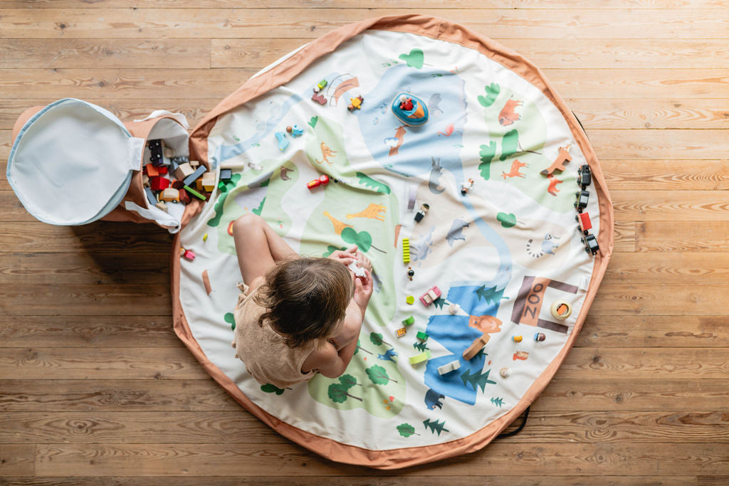 soo zoo, open basket and open mat, lots of toys, child is sitting on the mat and playing