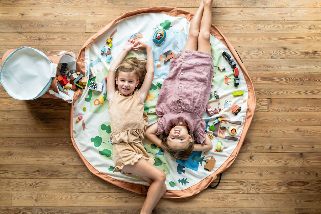 soo zoo, open basket and open mat with lots of toys, children are lying down on the mat