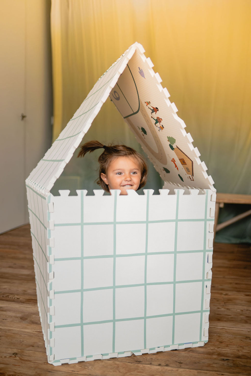 tiloo hopscotch, playhouse, grid design, child is sitting inside the house