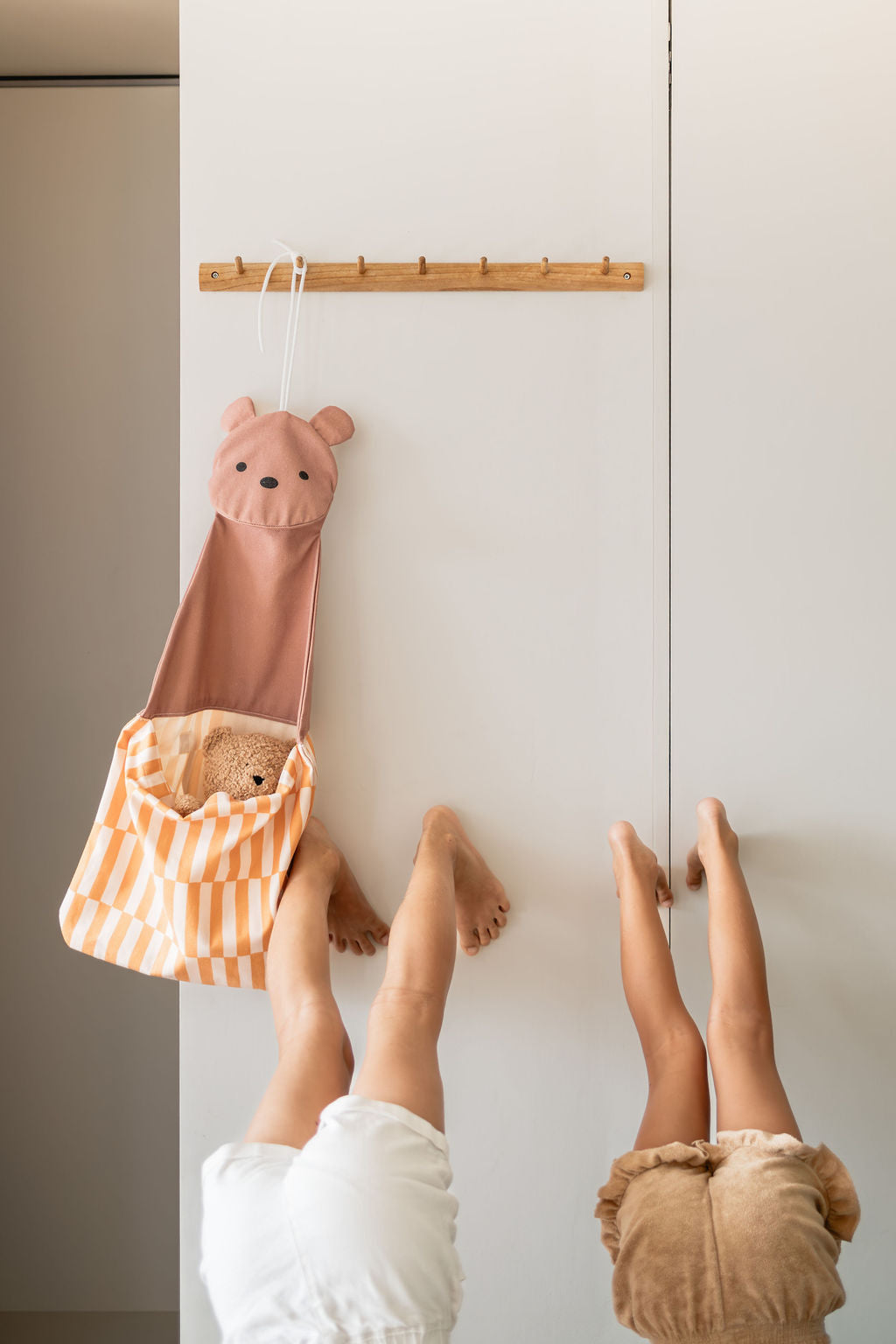 toto bear, hanging on coat rack, bear inside the bag, children are standing upside down against the wall