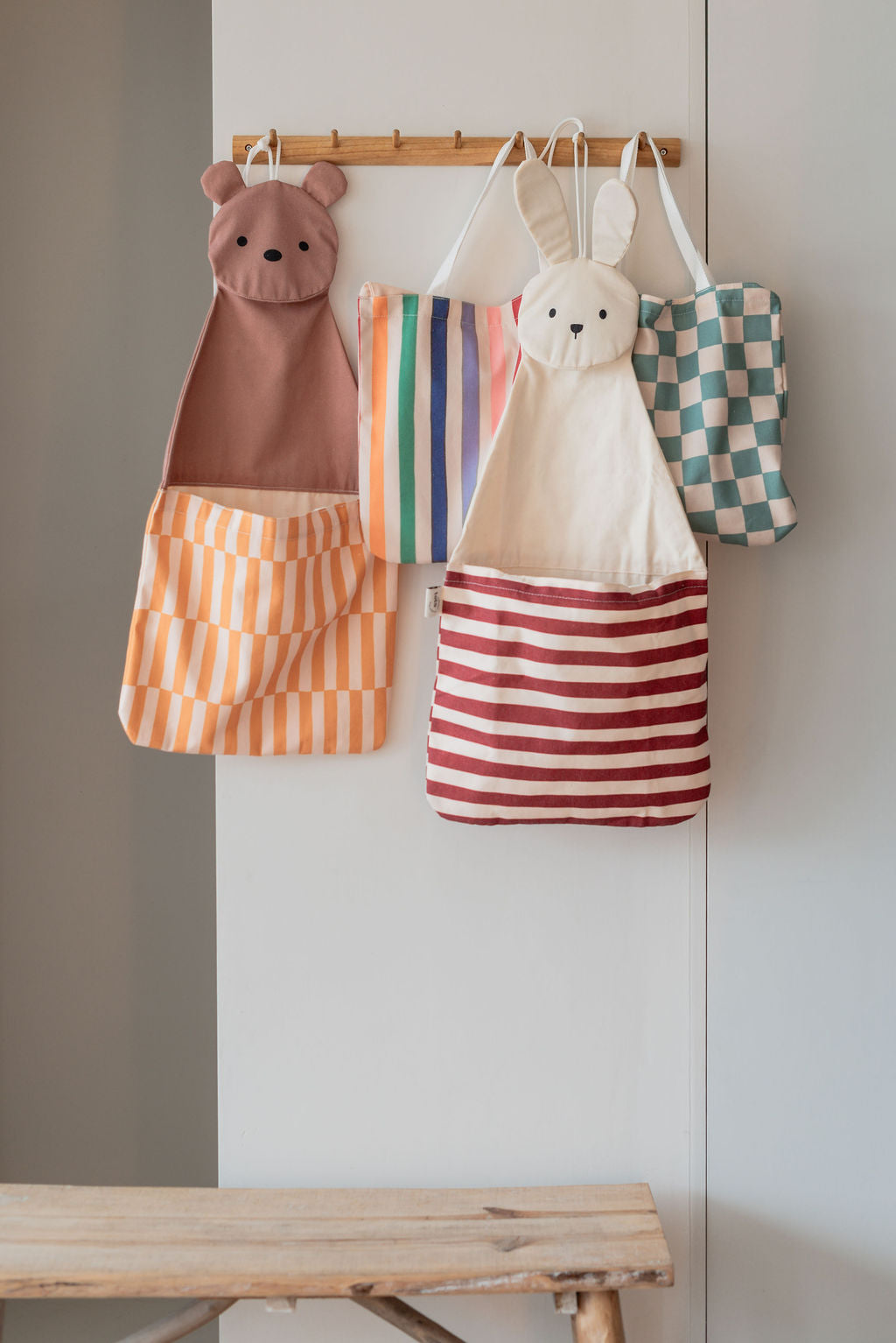 toto bear, bunny, dino and unicorn, all hanging on a coat rack on wall
