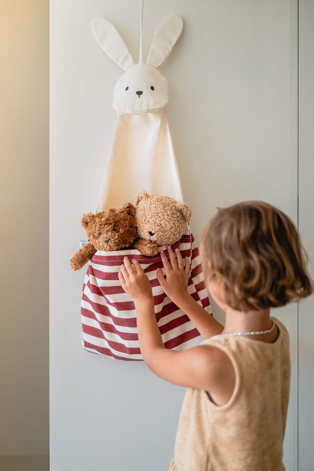 toto bunny, hanging on wall, child has put its 2 cuddle bears into the bag