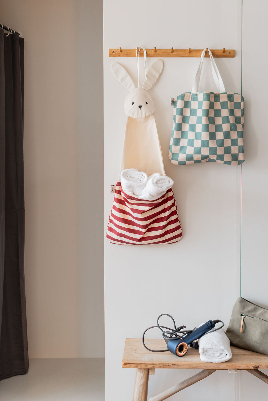 toto bunny, hanging on coat rack filled with towels, toto dino bag, hair dryer, towel and toiletry bag