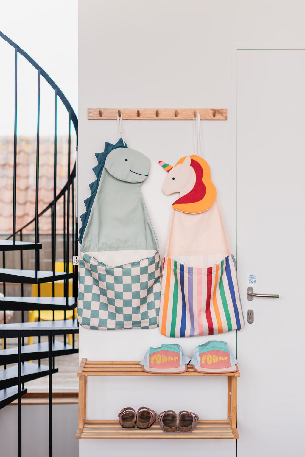 toto unicorn and toto dino, hanging on the wall, between door and stairs, shoes and caps