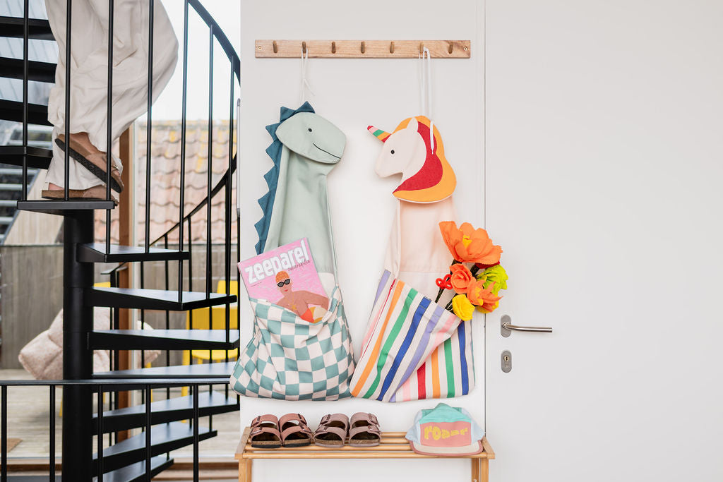 toto unicorn and toto dino, hanging on the wall next to door, shoes and cap