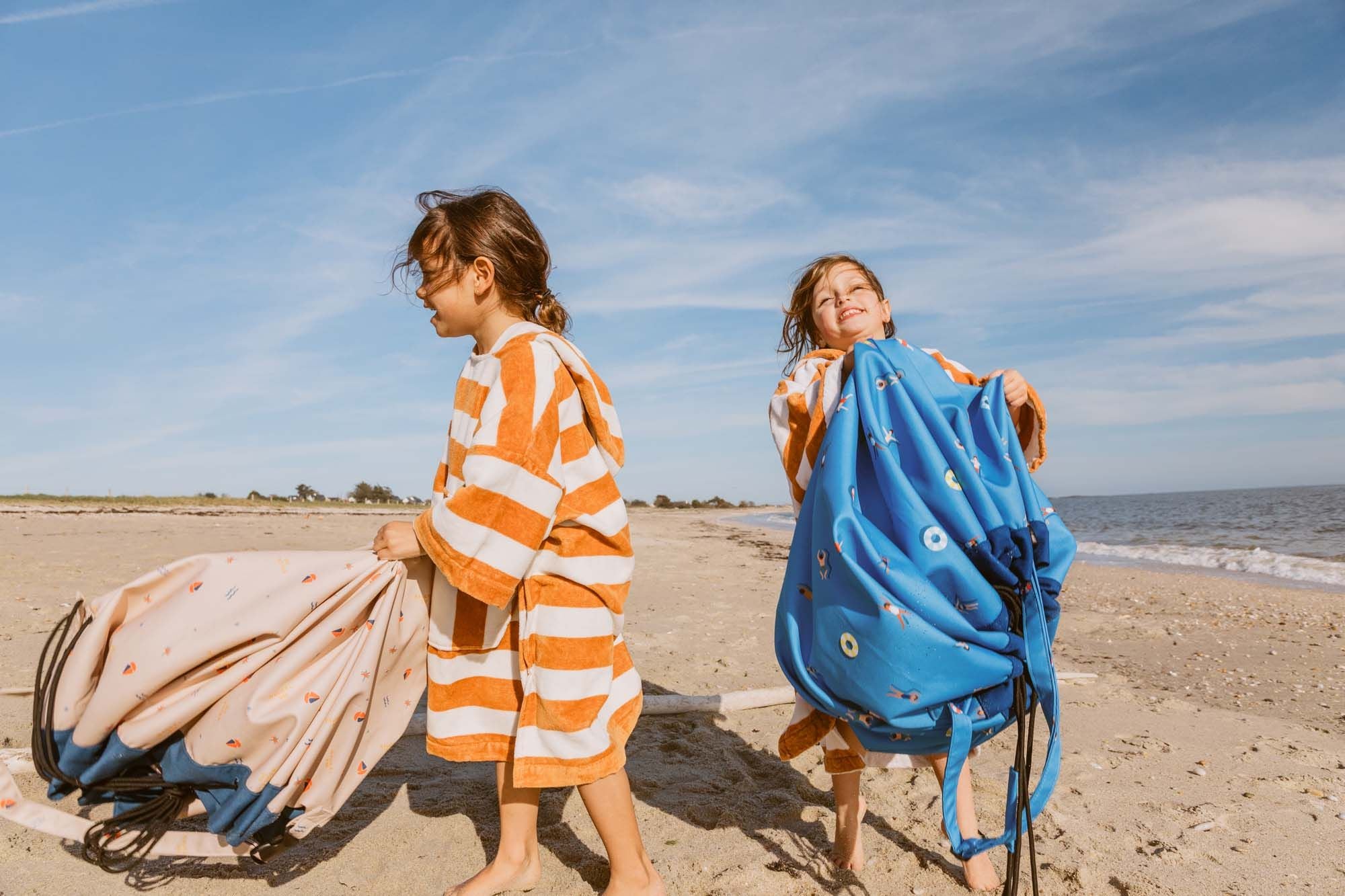 outdoor beach bags swim fun and magical days, children covered in towels are holding the bags at the beach