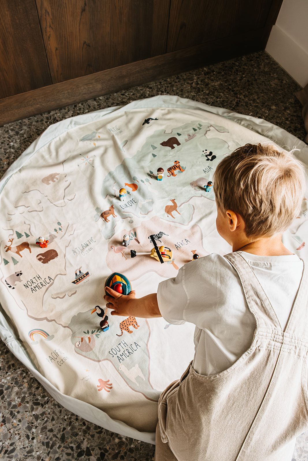 worldmap colors toy storage bag and playmat, child is playing on the mat