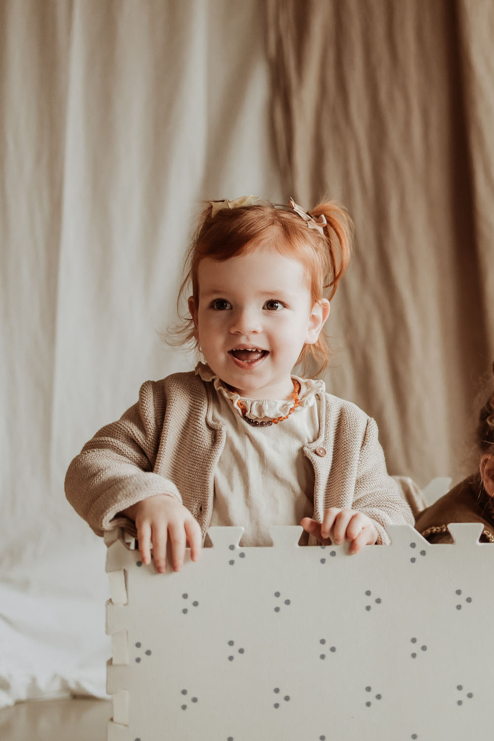 child laughing and standing in box made of dots puzzlemat