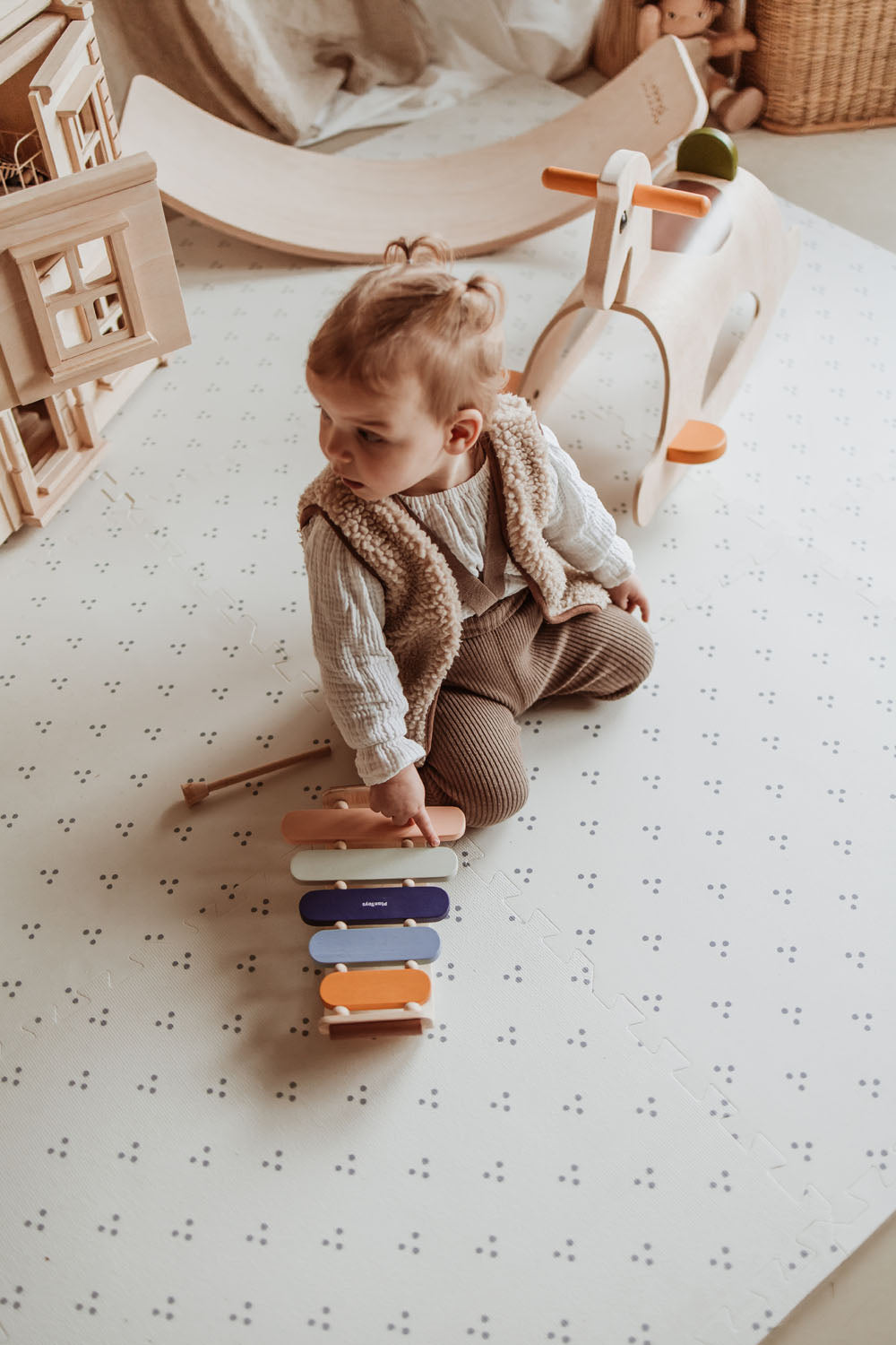 child playing with xylophone on dots puzzlemat, wooden rocking horse, slide and victorian play house