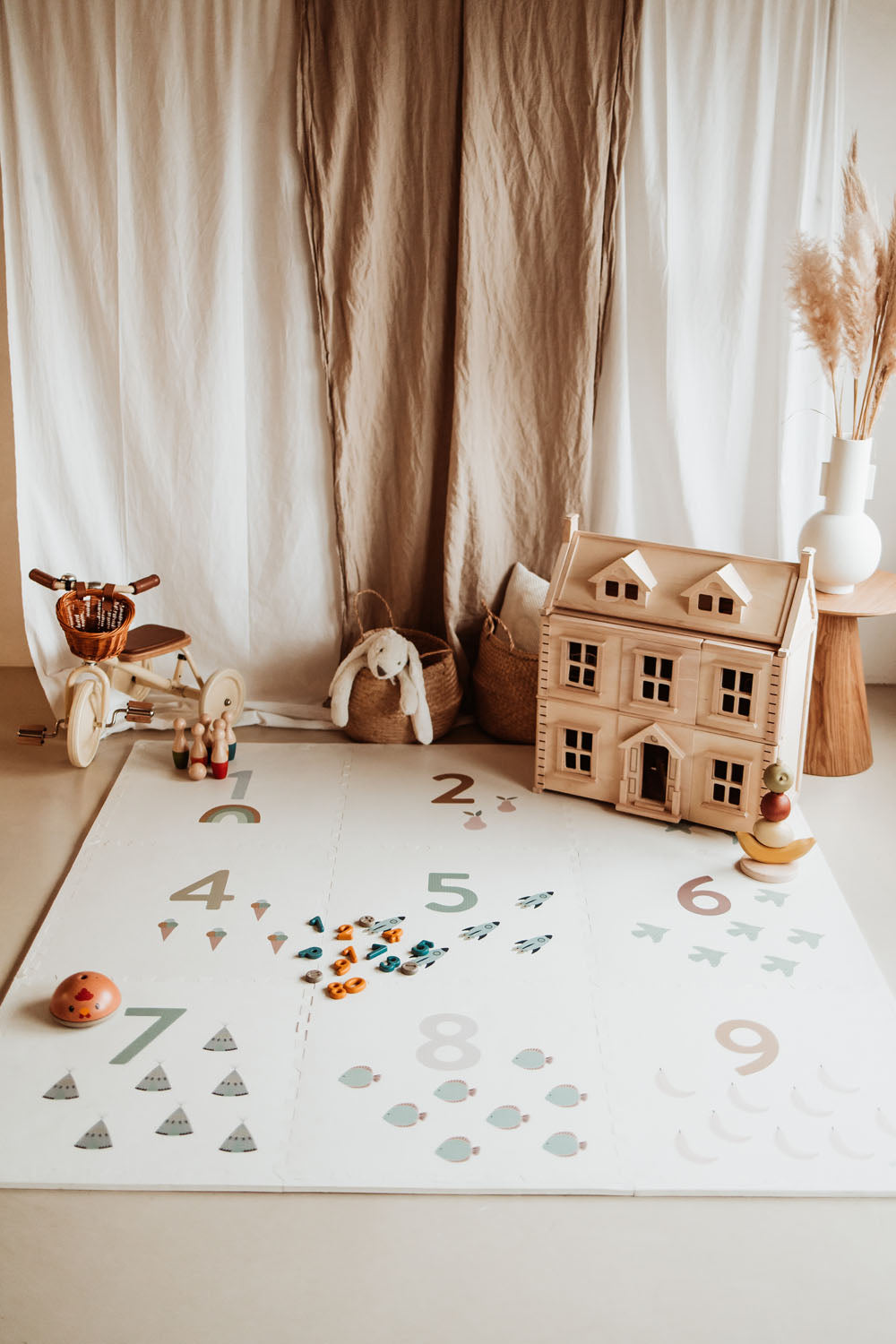 numbers puzzlemat lying on floor, lots of wooden toys as victorian play house and tricycle