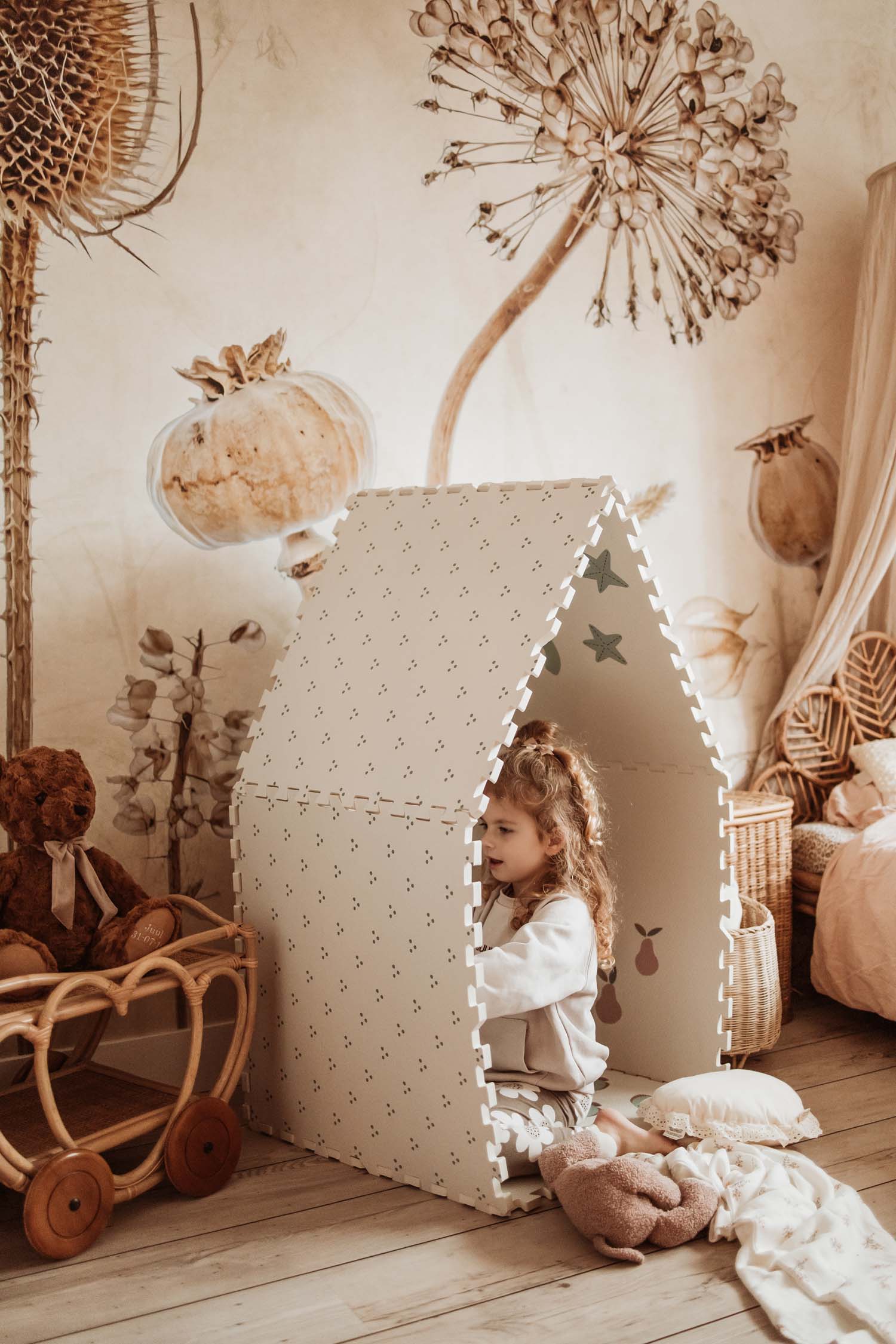 child playing in numbers/dots puzzlemat house, flowers print on wall