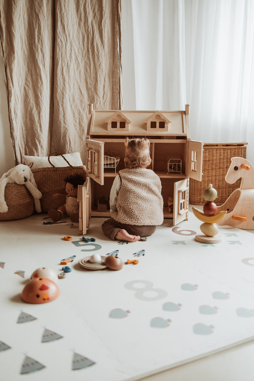 child playing on numbers puzzlemat with victorian play house, wooden toys, cuddles and rocking horse