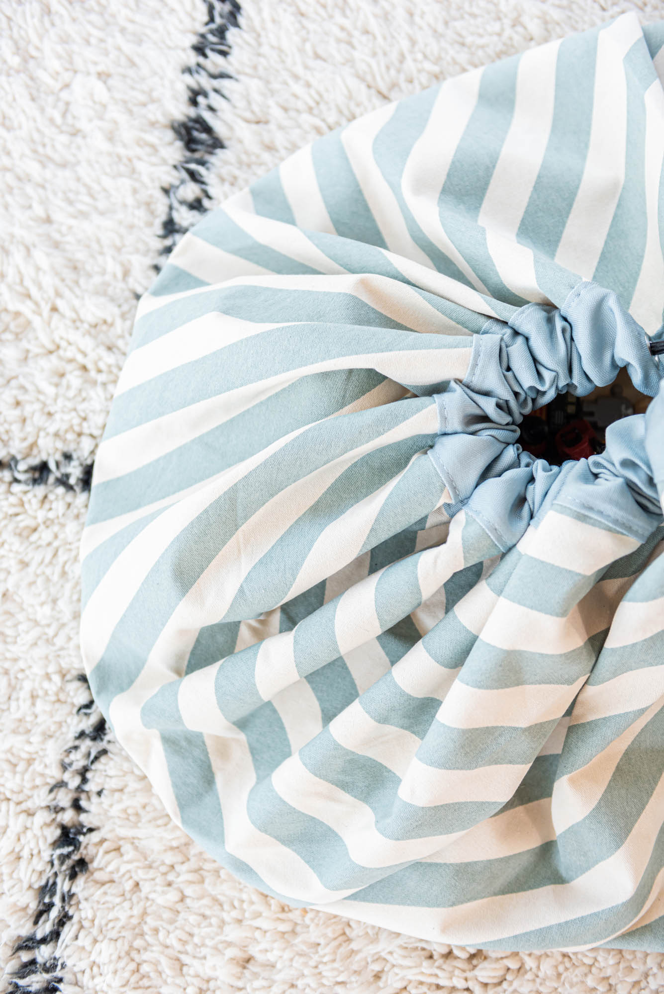 detail picture toy storage bag and play mat, green stripes, closed bag on white carpet