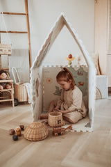 EEVAA worldmap puzzlemat, playhouse, child is sitting in the house playing with wooden basket and wooden toys