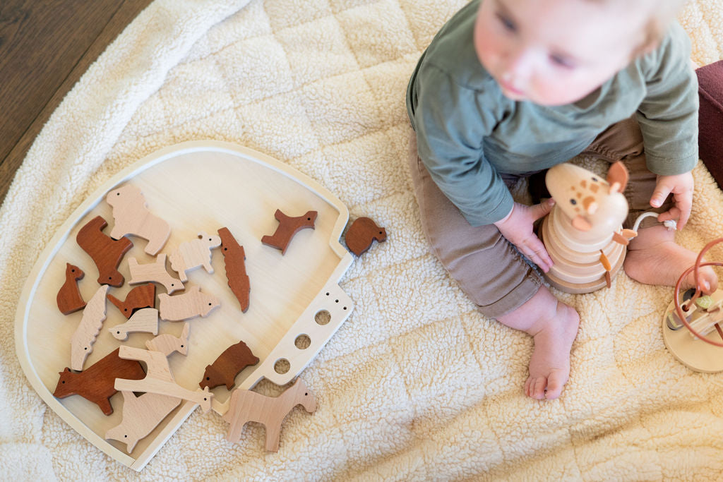 noomad soft teddy oak, child is sitting on the open mat, playing with wooden toys