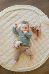 noomad soft teddy oak, baby is lying on the mat between soft cuddles