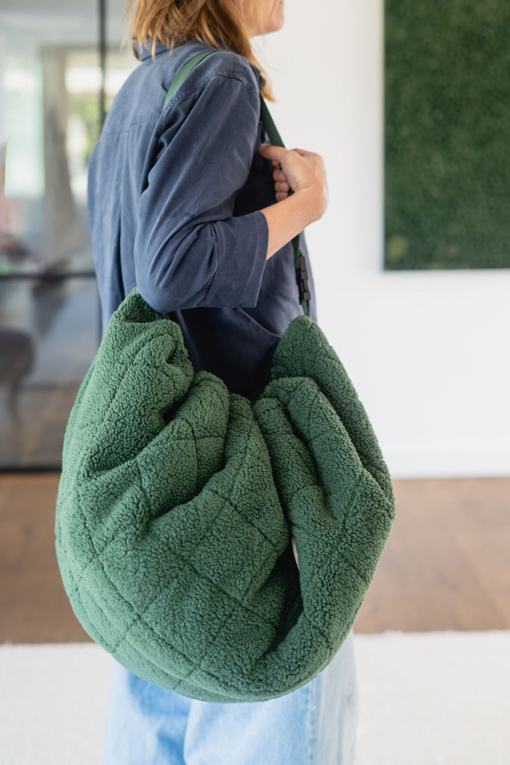 noomad soft teddy evergreen, adult is carrying the closed bag on the shoulder
