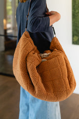 noomad soft teddy brown, person is carrying the closed bag on the shoulder