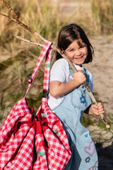 pic nic outdoor playmat, child is holding the closed bag on a branch of a tree