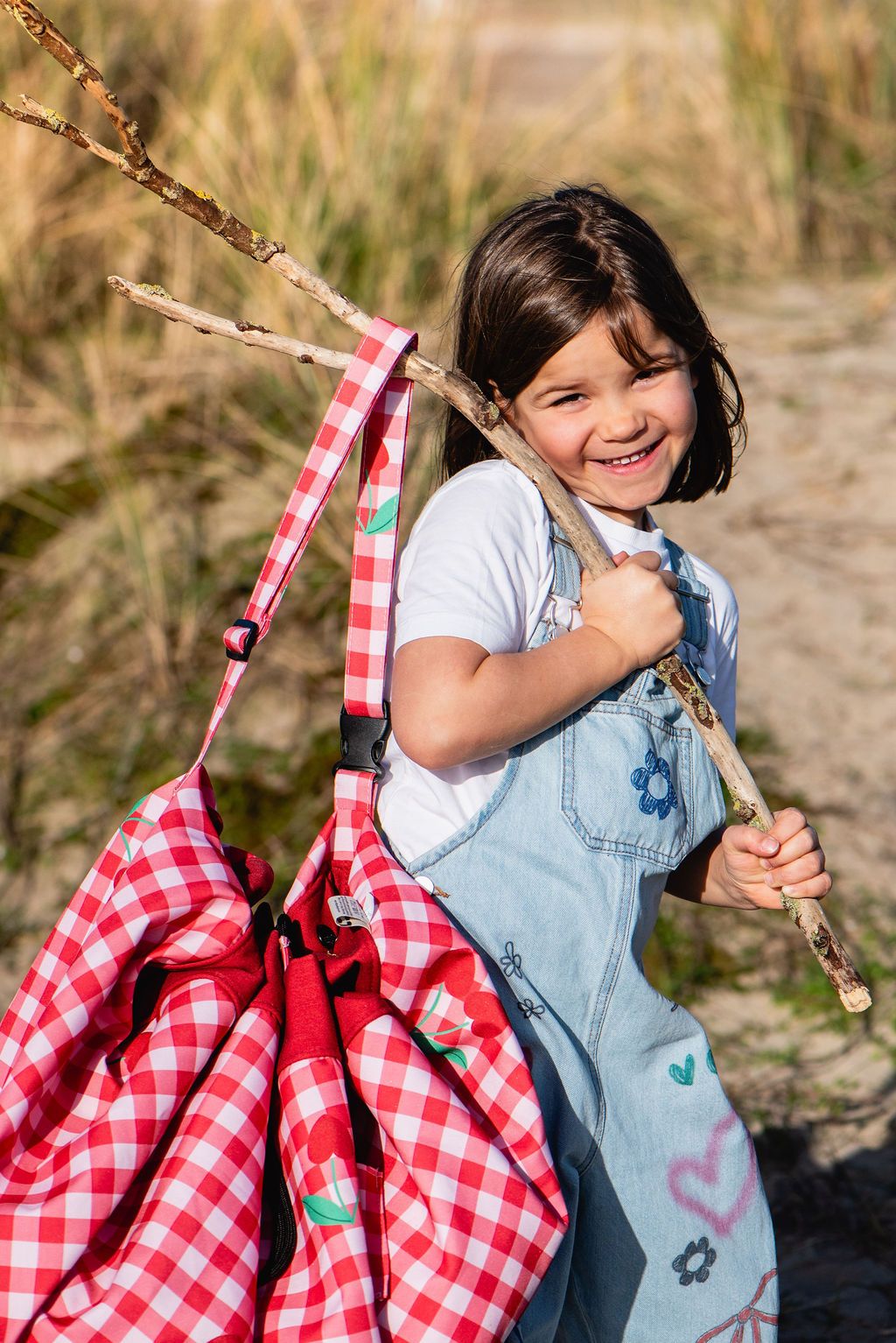 pic nic outdoor playmat, child is holding the closed bag on a branch of a tree