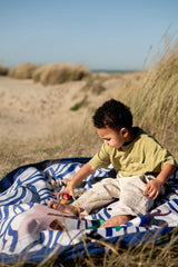 pirate outdoor playmat, child playing on a playmat in a natural setting with sand and grass.