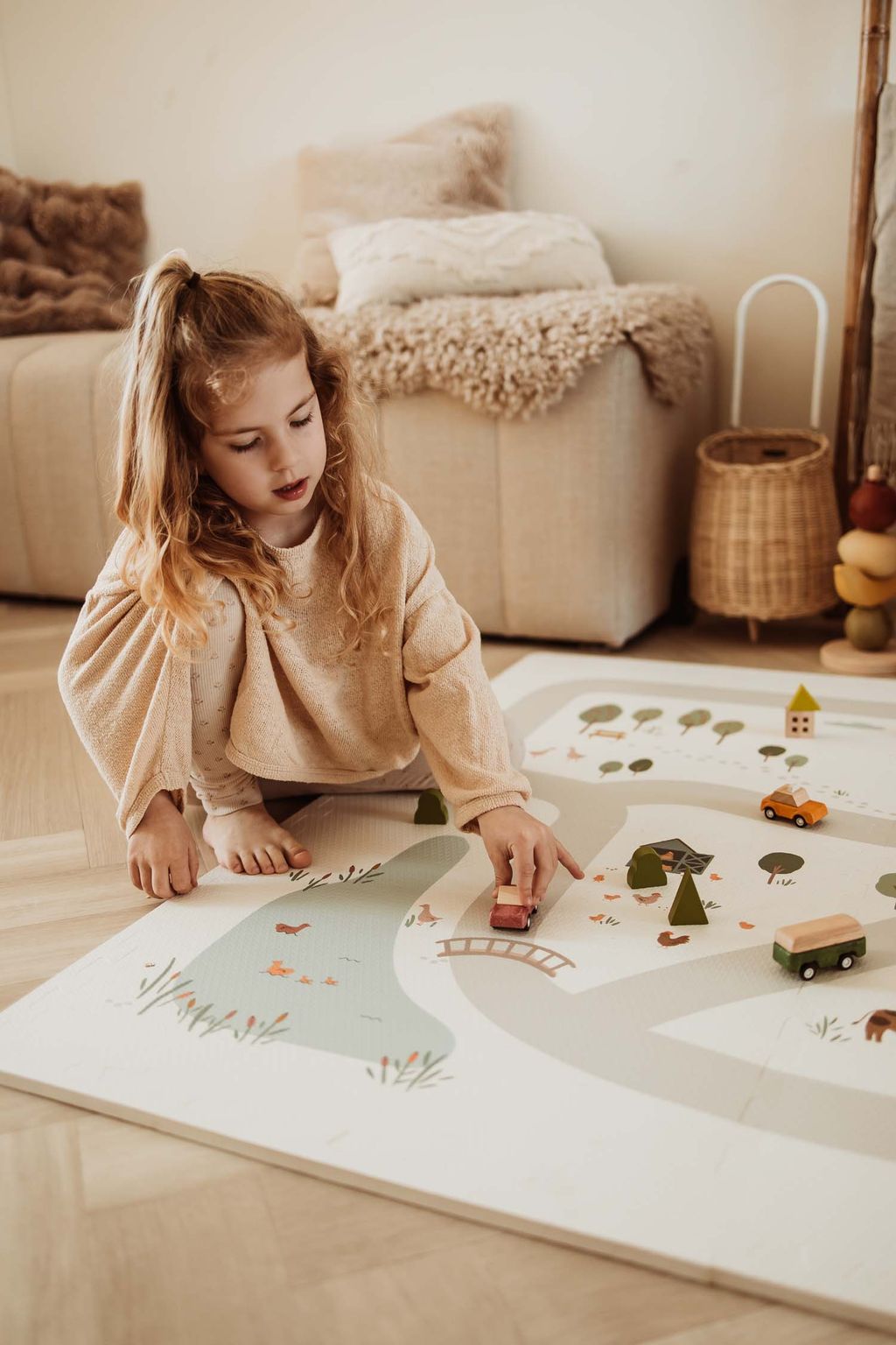 EEVAA farm puzzlemat, child is playing with wooden cars on the mat, wooden basket and sofa in the room