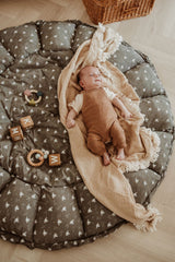 bloom birds babymat, open on floor, baby is lying on a blanket on the mat, wooden toys