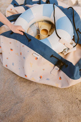 magical days outdoor beach bag, child is placing toys and swimming band in the bag