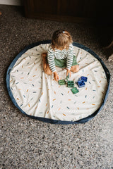 confetti toy storage bag and playmat, child is playing on the open mat