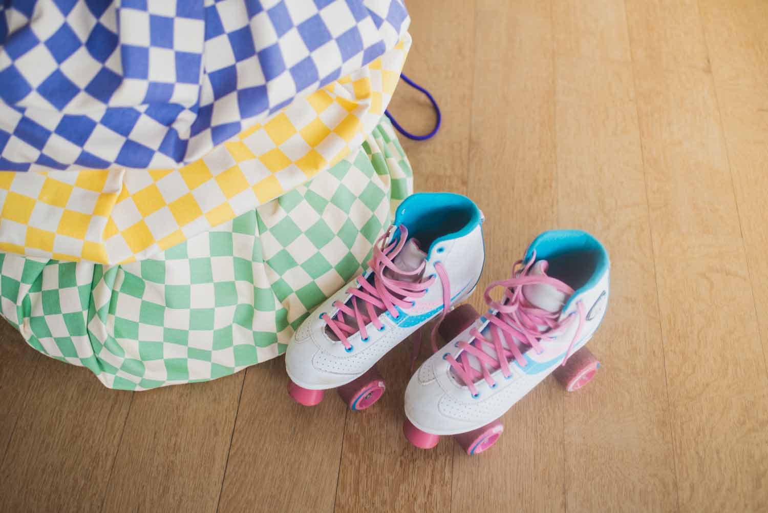vichy toy storage bags, all colors piled on top of each other, roller skates next to the bags on floor